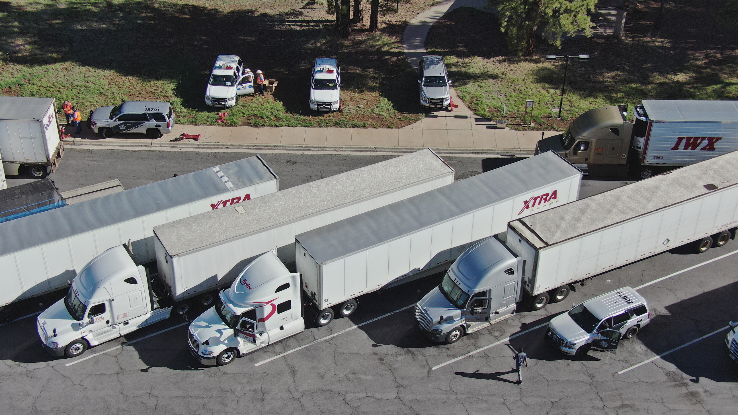 Tractor trailers and law enforcement vehicles are seen from above parked at an inspection area in northern Arizona