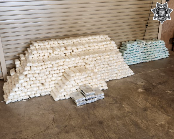 Piles of seized drugs wrapped in plastic packaging displayed on the ground 