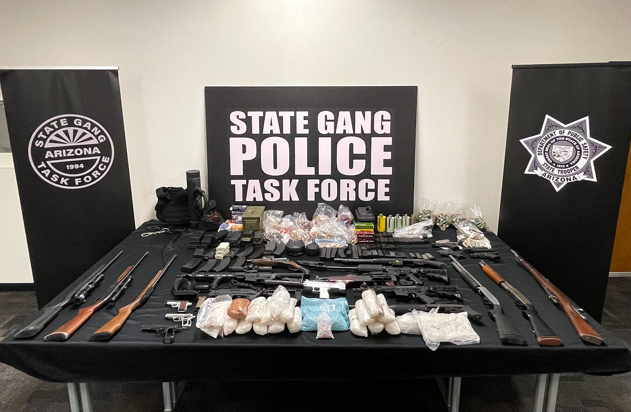 Drugs and weapons seized are displayed on a table