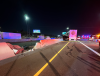 Nighttime crash scene on I-10 with two crashed vehicles and a crumbling barrier wall