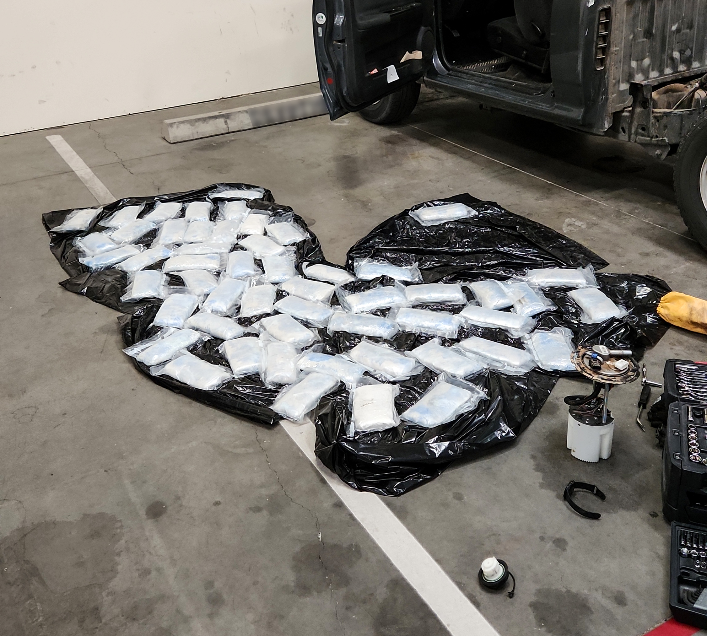 Plastic wrapped bundles on the ground next to a vehicle