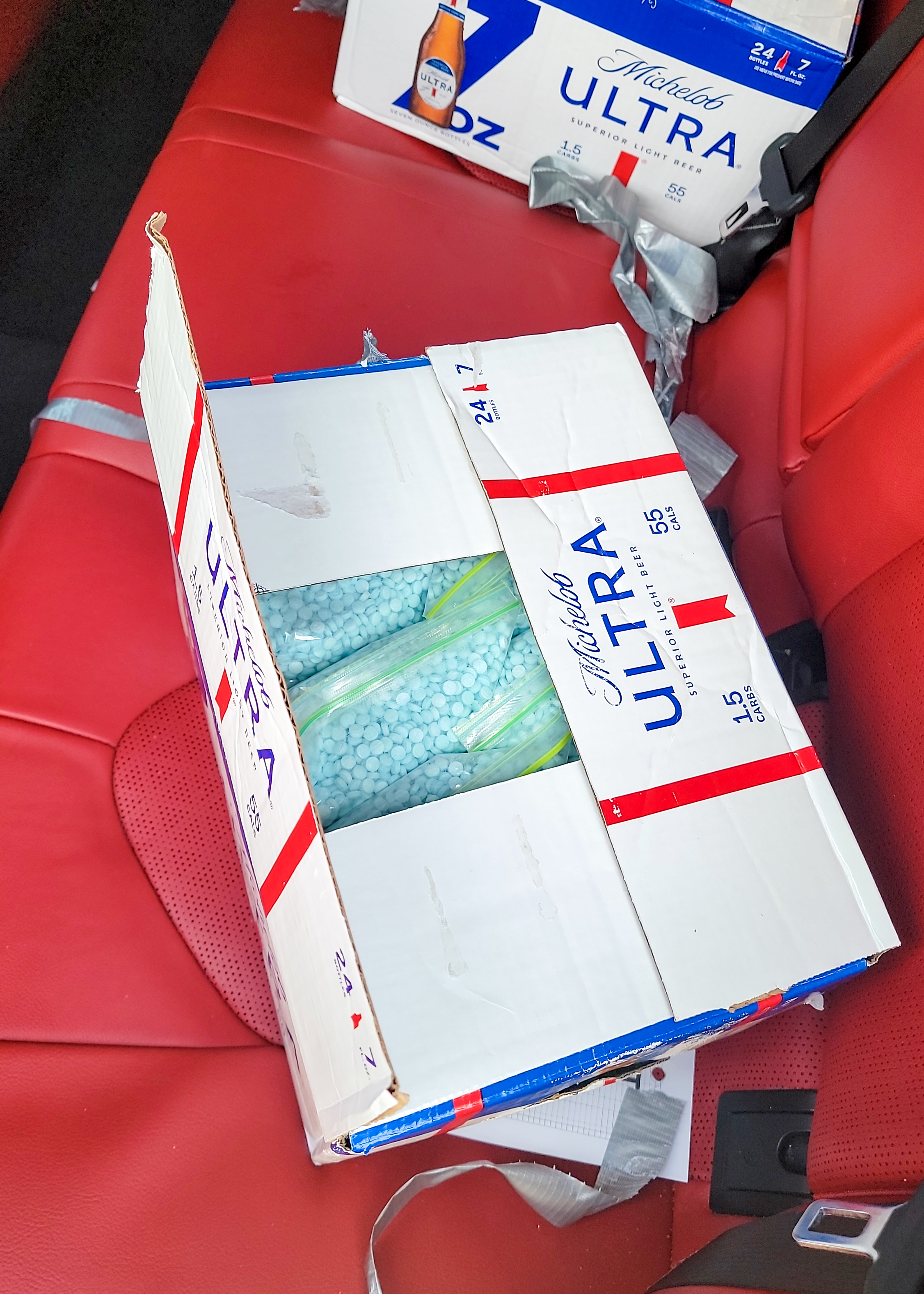 Bags of blue pills in beer box in the back seat of a car