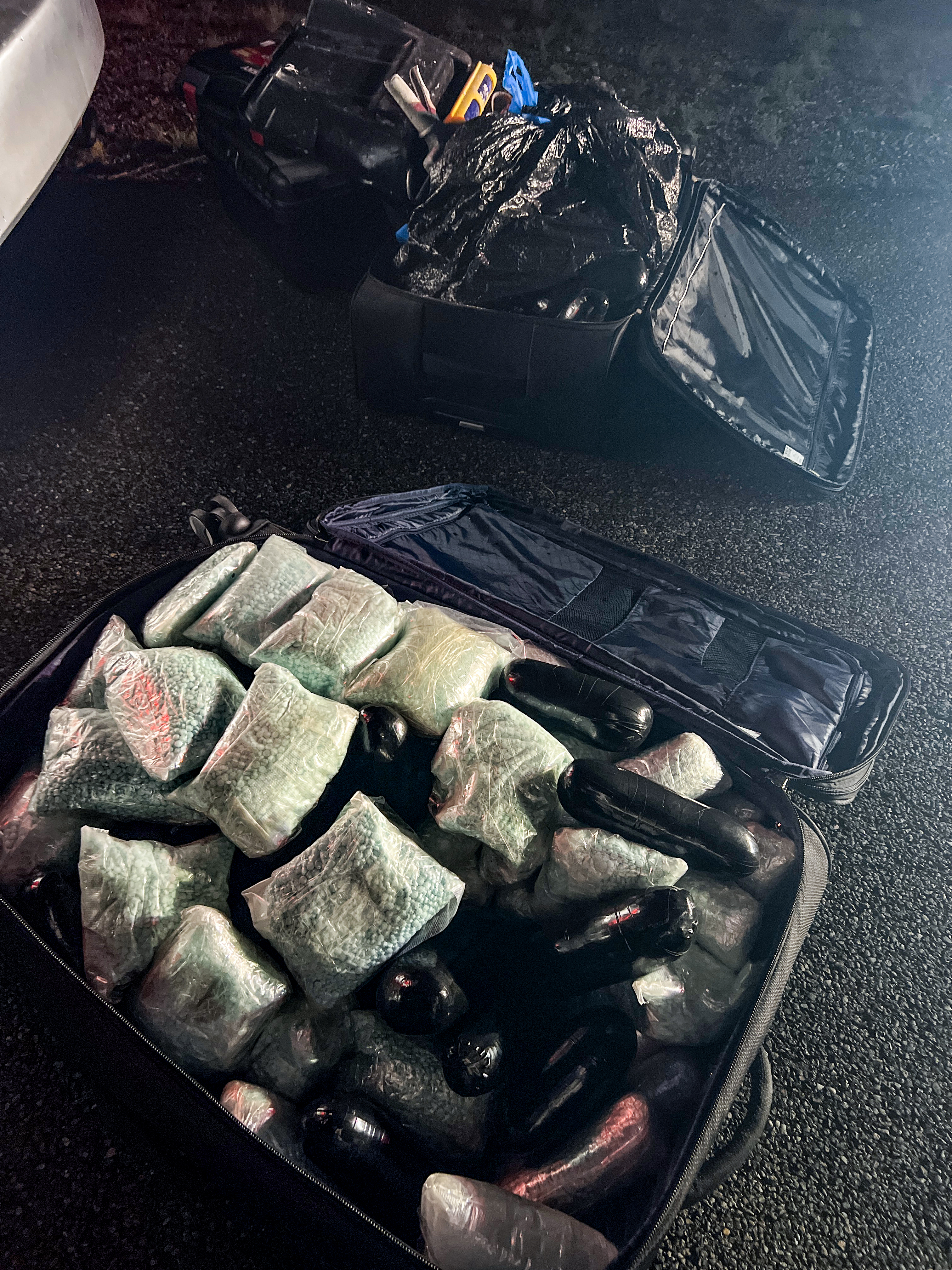 Overhead view of open luggage full of wrapped bundles of drugs 