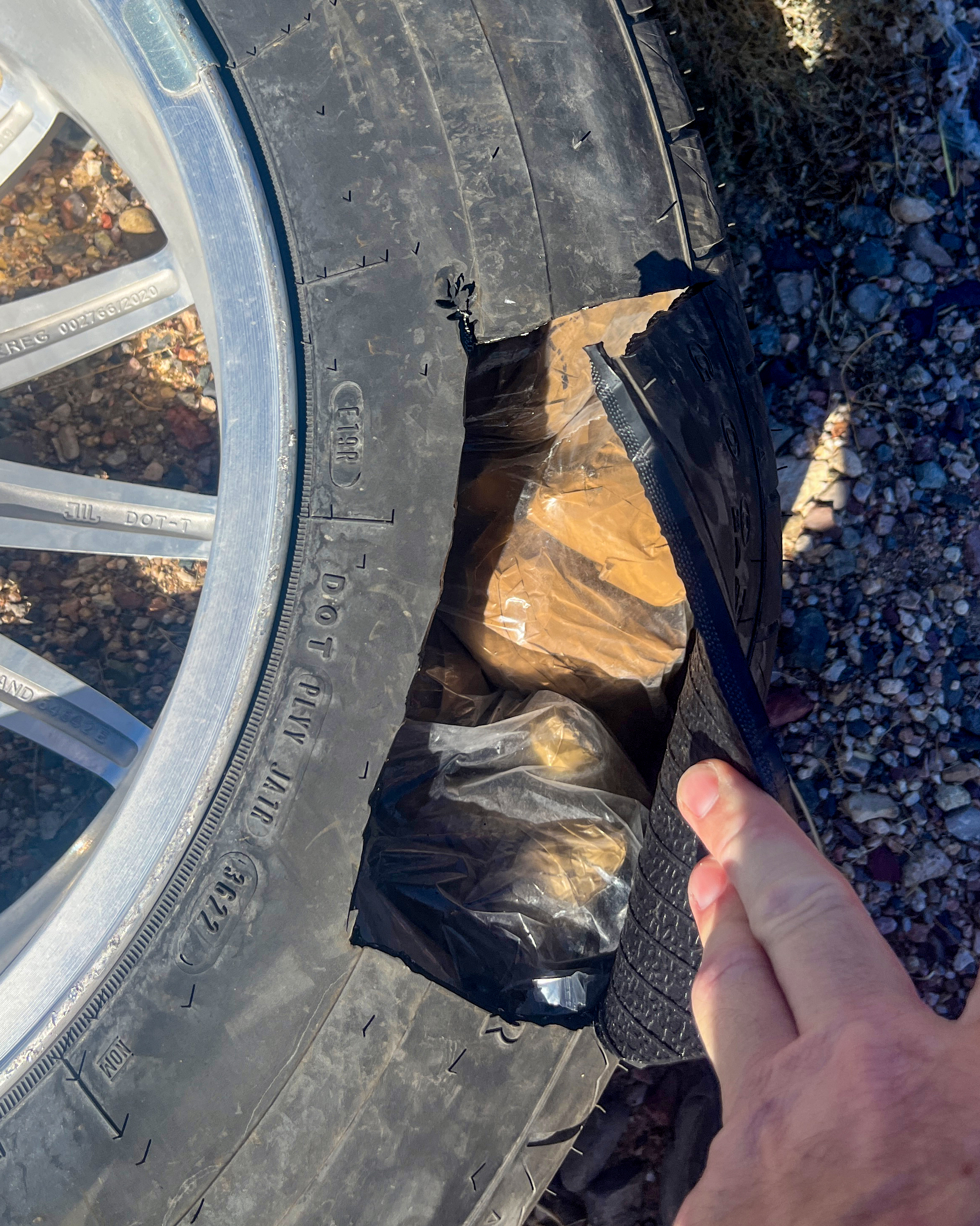 Plastic wrapped bundles are visible in a spare tire that's been cut open