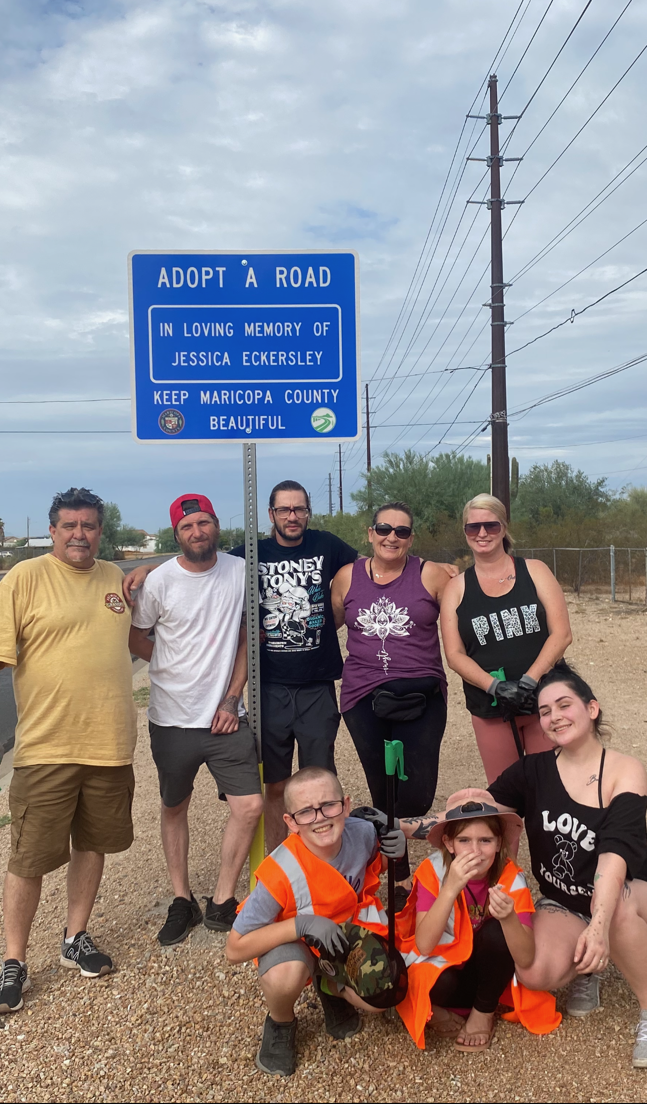 Jessica Eckersley's family and friends pose for a photo during a road cleanup in front of the "Adopt A Road" sign dedicated to Jessica