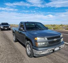 A pickup truck stopped beside the interstate with a police truck behind it