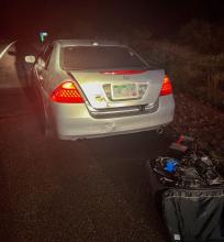 Honda sedan stopped beside highway with luggage on the pavement behind it