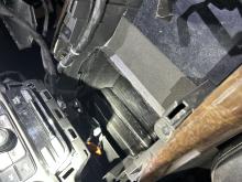 deconstructed center console of a vehicle revealing black tapped packages drugs hidden behind it. 