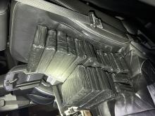 multiple black tapped packages of drugs in front seat of a car