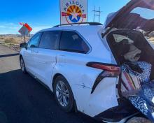 A white Toyota minivan stopped along I-40 with the trunk open and rugs hanging out of the back