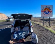 A white Toyota minivan stopped along I-40 with the trunk open and rugs hanging out of the back
