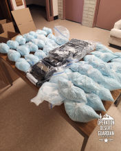Drugs seized by troopers--including plastic bags filled with small blue pills and tightly wrapped bricks of powder-- are displayed on a table
