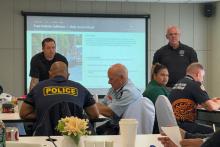 Captain Kramer and Captain Havens, stand at the front of a classroom speaking during a presentation.