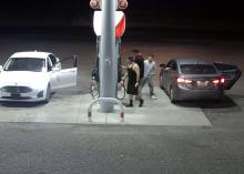 Screenshot from a gas station showing two cars parked at gas pumps. Three males are at the gas pumps.