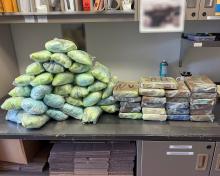 Photo of piles of plastic-wrapped blue pills and bricks of powder seized by troopers are displayed on a counter.