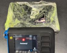Photo of a plastic-wrapped package of fentanyl powder and a drug testing device.