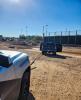 Trooper vehicle with a strap attached to a pickup truck in front of a baseball field