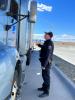 A CVETF Trooper looks up at the driver's side of a parked semi truck