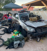 Firearms displayed on and around a vehicle in a messy yard