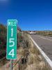 Highway milemarker sign in foreground, overturned vehicle in background