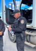 An ADOT officer with the ACVSP stands beside the cab of a truck speaking with a driver.