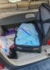 Numerous plastic bags full of blue pills are seen inside an open suitcase in the trunk of a vehicle