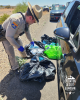 An AZDPS state trooper stands beside a vehicle on the roadside and sorts through trash bags with blue pills visible inside