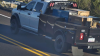 Image of a white Dodge Ram 5500 truck with a black bed and red and blue lights taken from a roadway camera