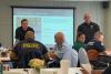 Captain Kramer and Captain Havens, stand at the front of a classroom speaking during a presentation.