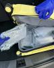 Plastic wrapped packages of cocaine are visible inside a partially open yellow rolling suitcase