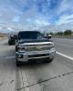 A gray Chevrolet pickup truck stopped on the shoulder of a highway with AZDPS vehicles behind it.
