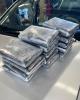 Plastic-wrapped packages of fentanyl powder are stacked on the hood of a vehicle.