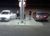 Screenshot from a gas station camera showing two cars parked at gas pumps. Three males are at the gas pumps.